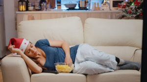 sleepy woman with holiday blues watching television on sofa